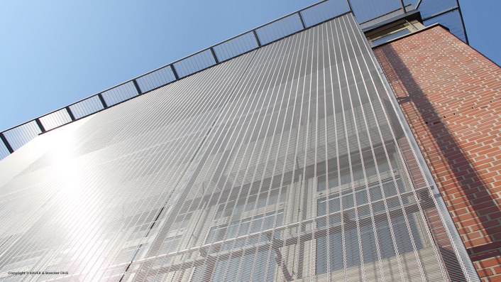 The facade using metal wire mesh creates a unique modern design for the building