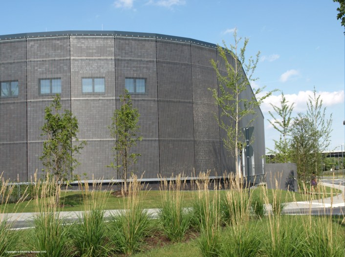 A building with an arched metal facade. Wire mesh is used on the facade.